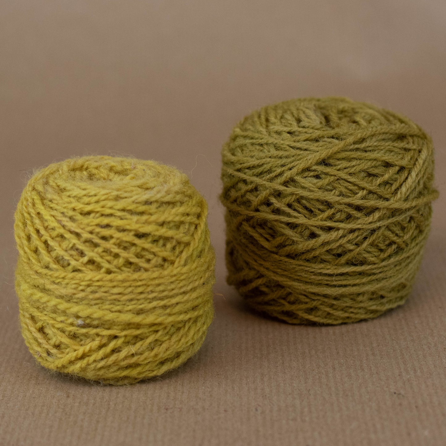 Two balls of green yarn on a beige background