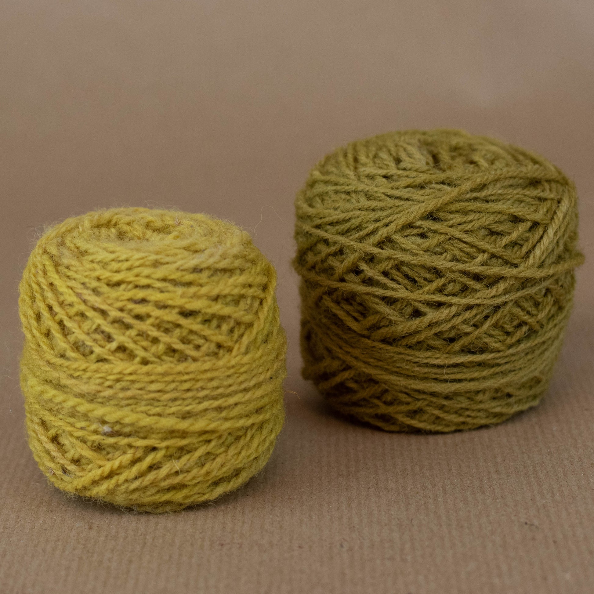 Two balls of green yarn on a beige background