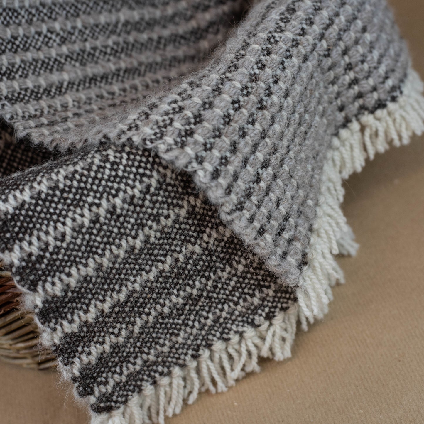 Textured blanket with fringe on a brown surface