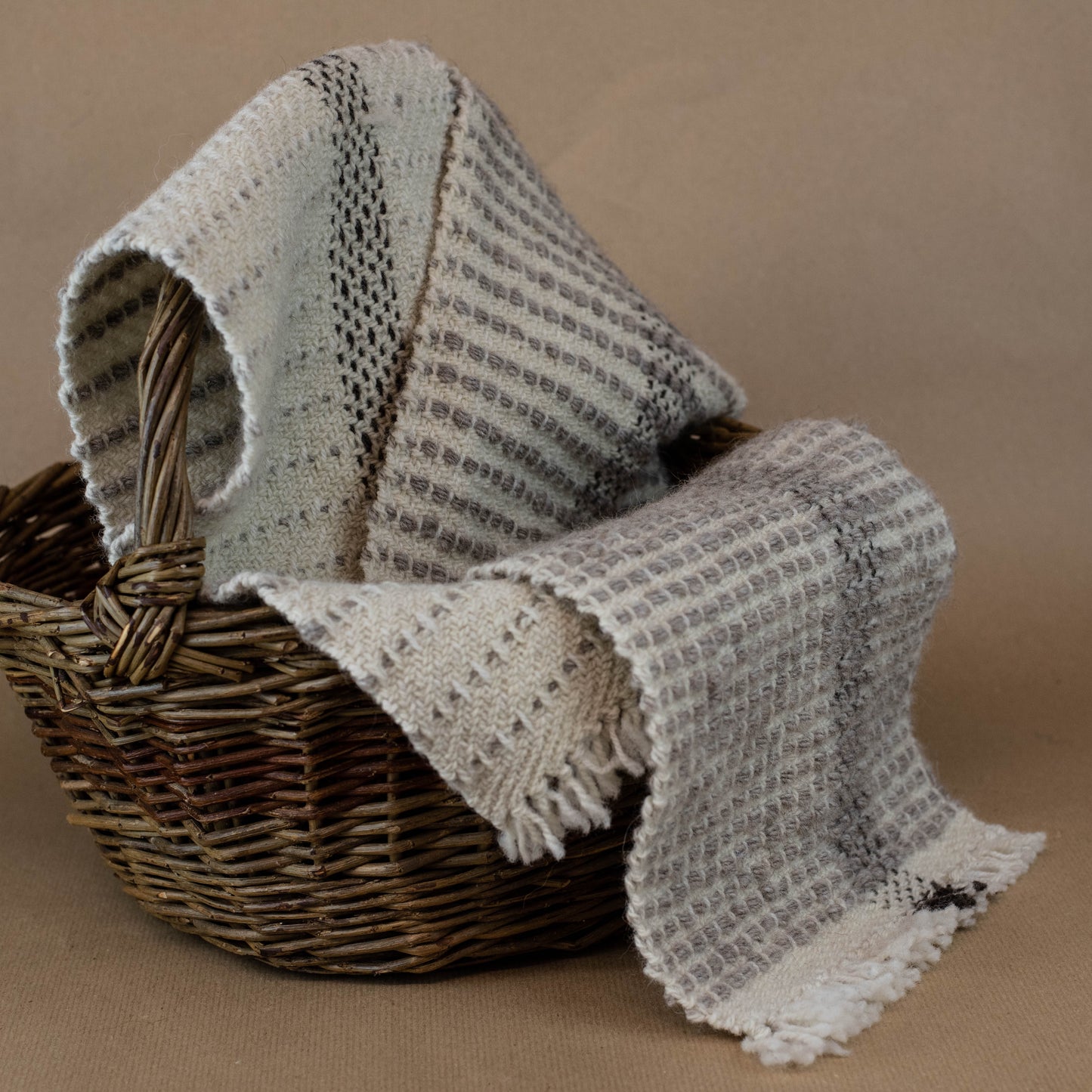 Textured fabric draped over a wicker basket on a brown background