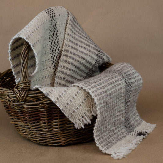 Textured fabric draped over a wicker basket on a brown background