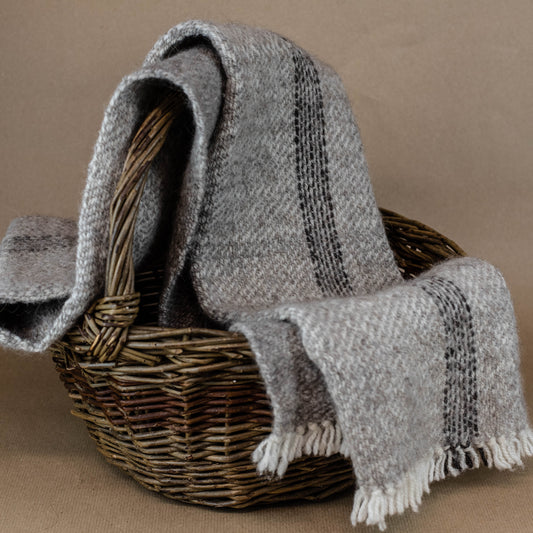 Woven basket with a gray striped blanket draped over it on a brown background