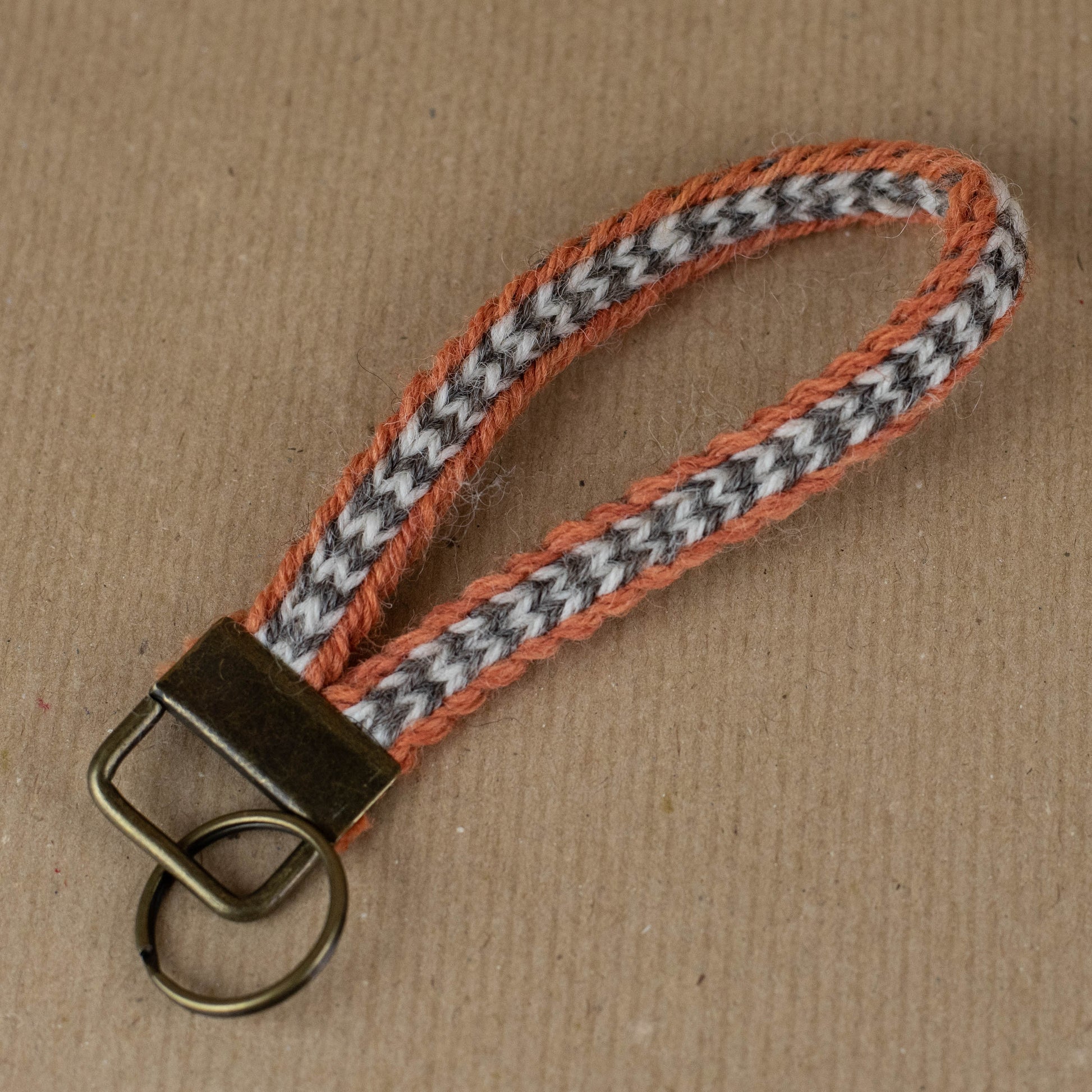 Keychain with orange and gray woven strap on a brown background