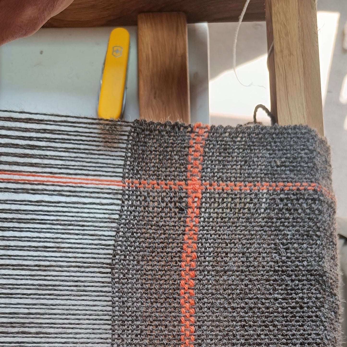 Textile material on a loom with a red stripe