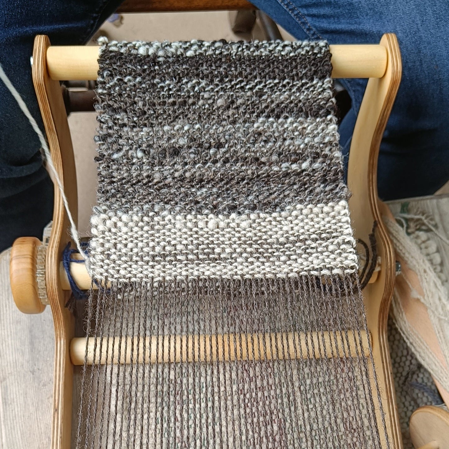 Handloom with woven fabric on a wooden frame, showing the process of textile creation.