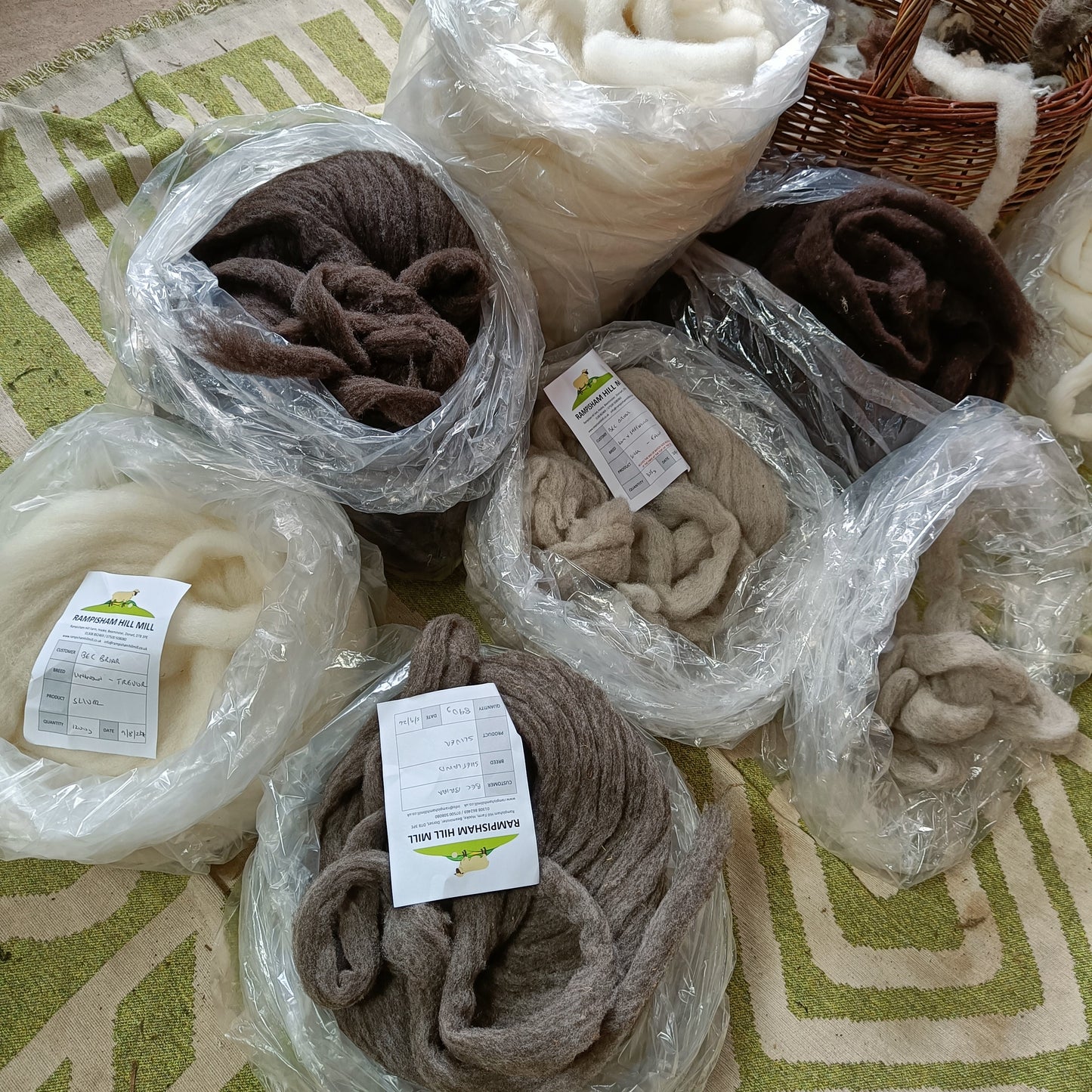 Bundles of sliver wool in various colors wrapped in plastic on a patterned surface