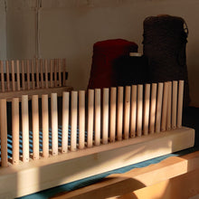 Load image into Gallery viewer, Image of a peg loom set with yarn in the background.
